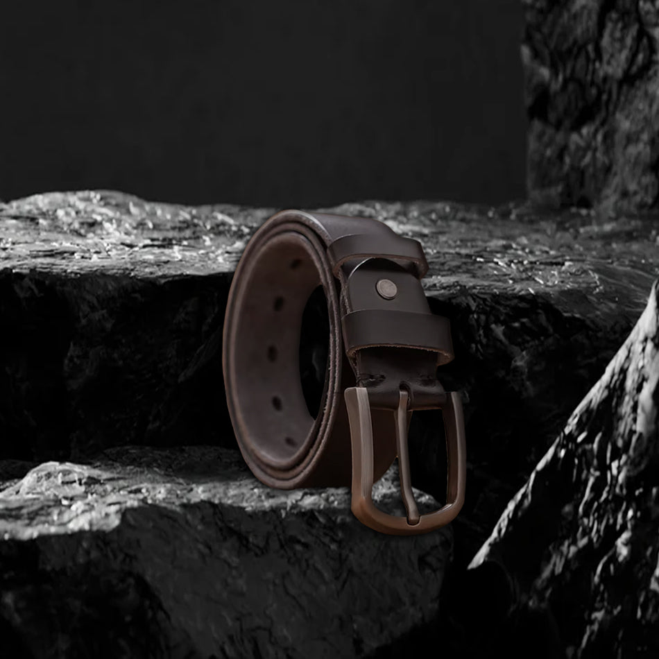 Echtleder-Gürtel aus dunklem Rindsleder auf schwarzem Steinfelsen – Seitenansicht mit Metallschnalle