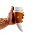 Weisser Thermobecher im Wikinger-Horn-Design mit braunem Lederhalter, fest umschlossen in starker Männerhand