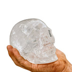 Massiver Kristall-Totenkopf 1500-1600g aus echtem Bergkristall – gehalten in kräftiger, verschmutzter Männerhand auf weissem Hintergrund. Symbol für Stärke, Energie, Klarheit und nordische Handwerkskunst.