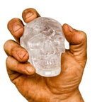 Kristall-Totenkopf aus echtem Bergkristall (800–850 g) – gehalten in kräftiger, leicht verschmutzter Männerhand auf weissem Hintergrund. Handgeschliffener Kristallschädel, Symbol für Stärke, Klarheit, Energie und nordische Handwerkskunst.