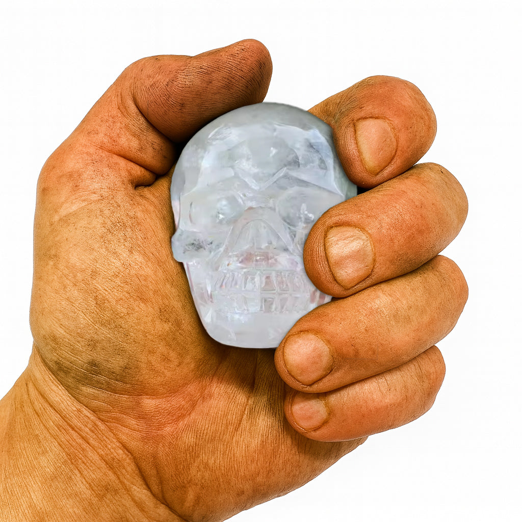 Kleiner Kristall-Totenkopf aus echtem Bergkristall (150–200 g) – gehalten in kräftiger, leicht verschmutzter Männerhand. Handgeschliffener Kristallschädel, Symbol für Stärke, Klarheit, Energie und nordische Handwerkskunst.