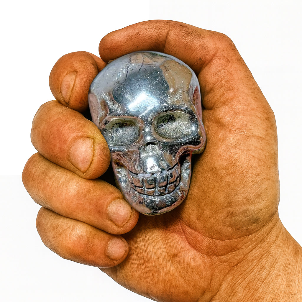 Echter Pyrit-Totenkopf, gehalten in kräftiger, rauer Männerhand. Polierter Wikinger-Schädel aus Stein – Symbol für Stärke, Mut, Erdverbundenheit und Handwerkskunst.
