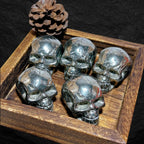 Fünf glänzende Pyrit-Totenköpfe in rustikaler Holzbox mit Tannenzapfen – edle Wikinger-Schädel aus massivem Pyrit, Symbol für Stärke, Mut, Schutz und nordische Handwerkskunst.
