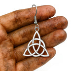 Glänzender Edelstahl Triquetra Ohrring in einer leicht schmutzigen Wikingerin-Hand.