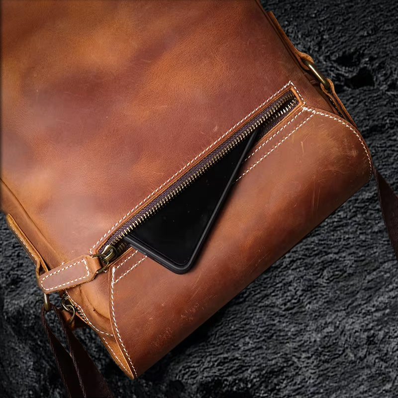 Umhängetasche aus Echtleder – Rückansicht mit Reissverschlussfach auf schwarzem Steinfelsen