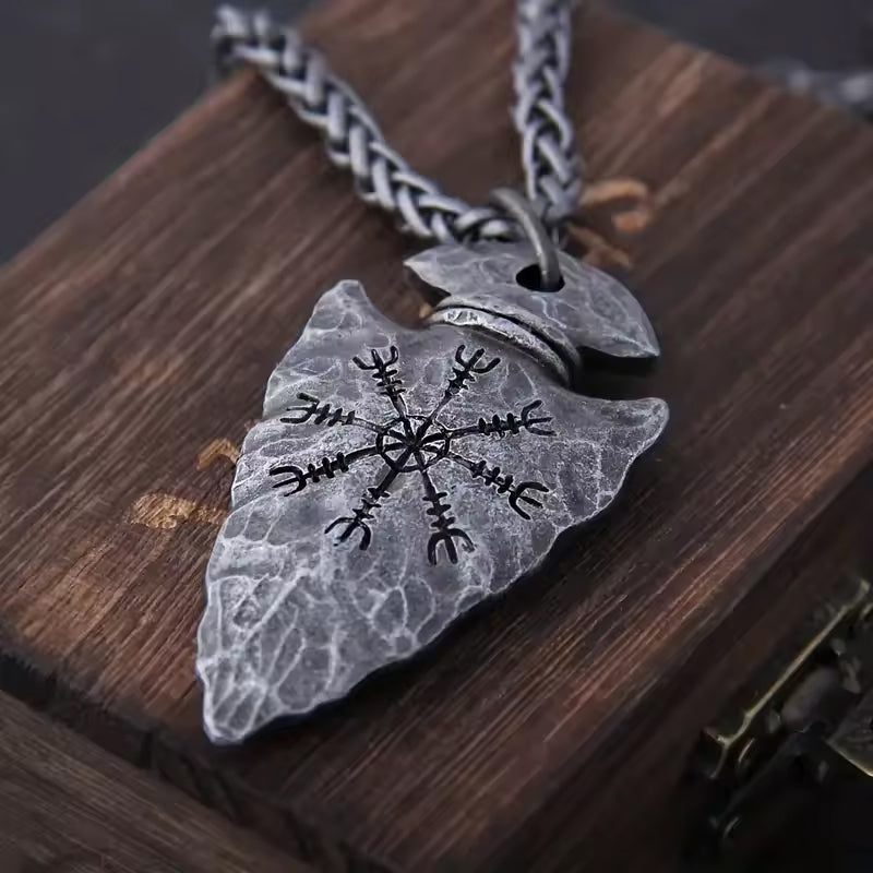 Vegvisir Arrowhead Wikinger Halskette aus Metall, detailreich graviert mit nordischem Schutzsymbol, liegend auf einer hölzernen Oberfläche.