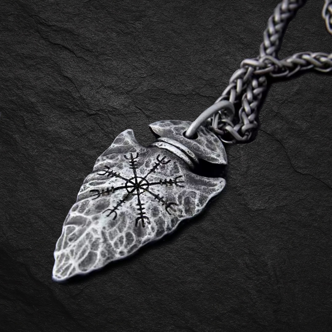 Vegvisir Arrowhead Wikinger Halskette mit graviertem nordischen Wegweiser-Symbol, Nahaufnahme des Anhängers auf dunklem Stein-Hintergrund.