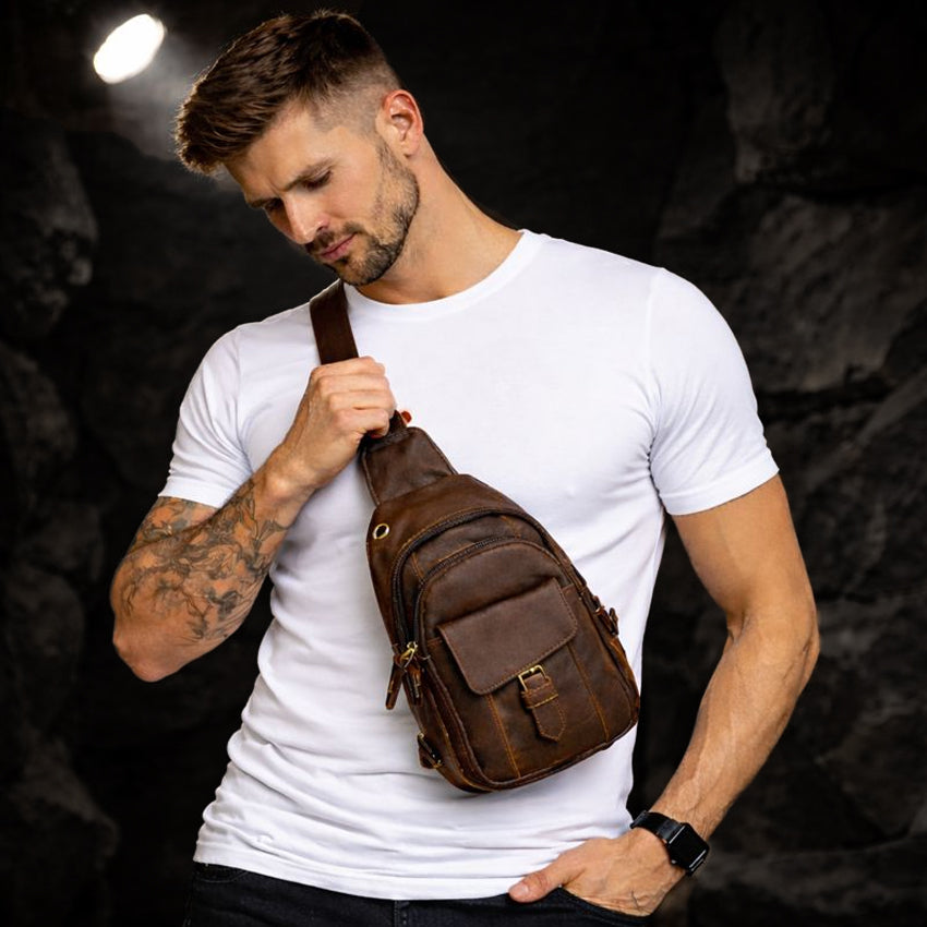 Echtleder Umhängetasche Herren aus Rindsleder, braune Tasche getragen am Model vor dunklem Felsenhintergrund